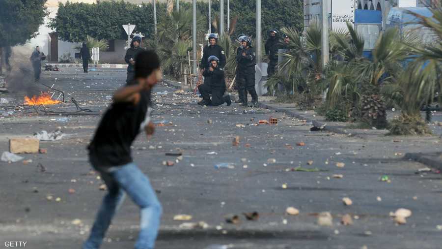أحد المتظاهرين يرشق الأمن التونسي بالحجارة يوم 10 يناير 2011 في الرقاب وأحد أفراد الأمن يطلق الرصاص نحوه