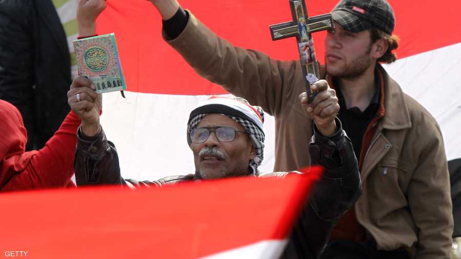 متظاهر يحمل القرآن بيد والصليب بيده الأخرى في ميدان التحرير