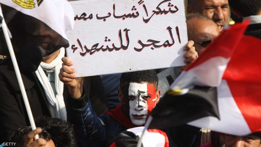 متظاهر يحمل لافتة لتحية المتظاهرين وضحايا الثورة