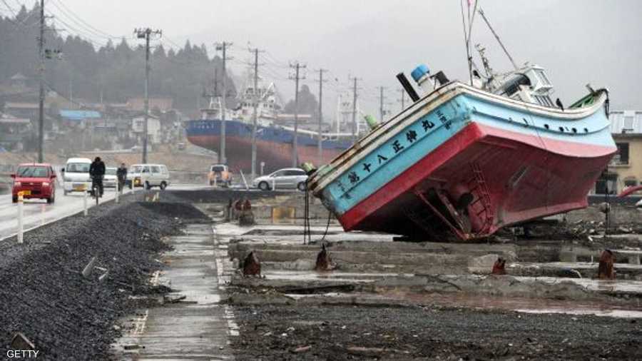 مركب قلبتها أمواج تسونامي.. وسيارات تمضي على طريق استعادة الحياة الطبيعية.