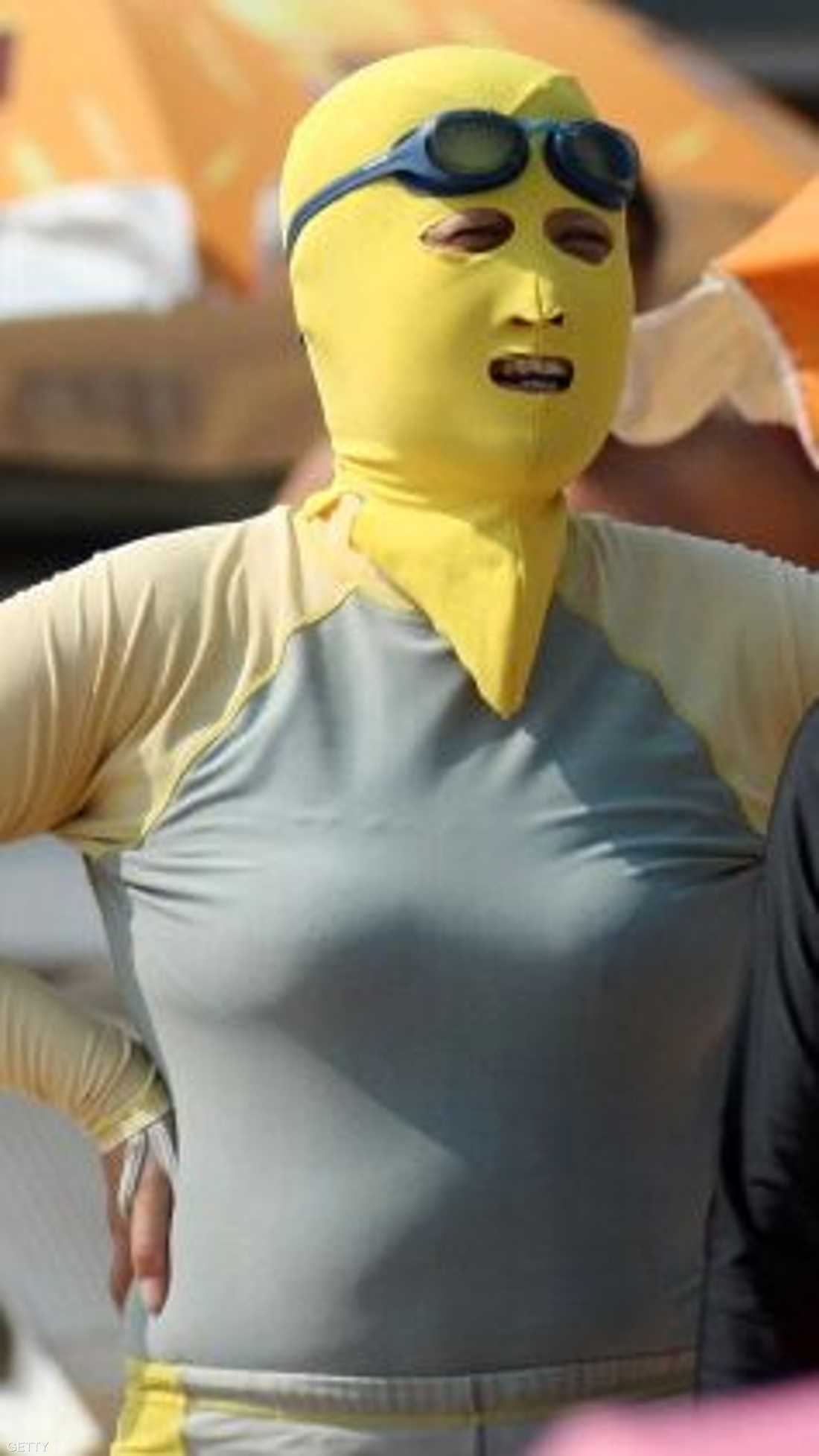 صينيتان ترتديان ملابس سباحة وتغطيان وجهيهما بقناع للحماية من أشعة الشمس على شاطئ مدينة كينغداو