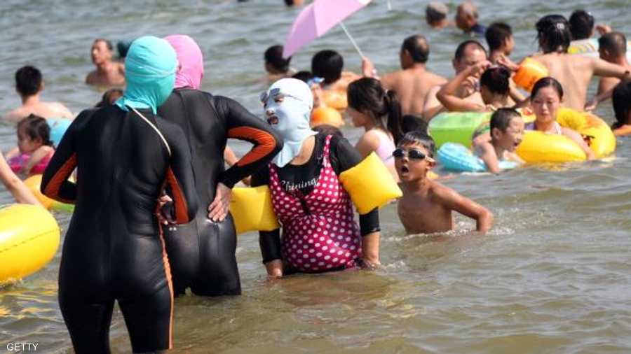 شاطئ كينغداو أصبح يعج بالمقنعين إلى جانب المستجمين الذين لا يخشون أشعة الشمس كما يبدو