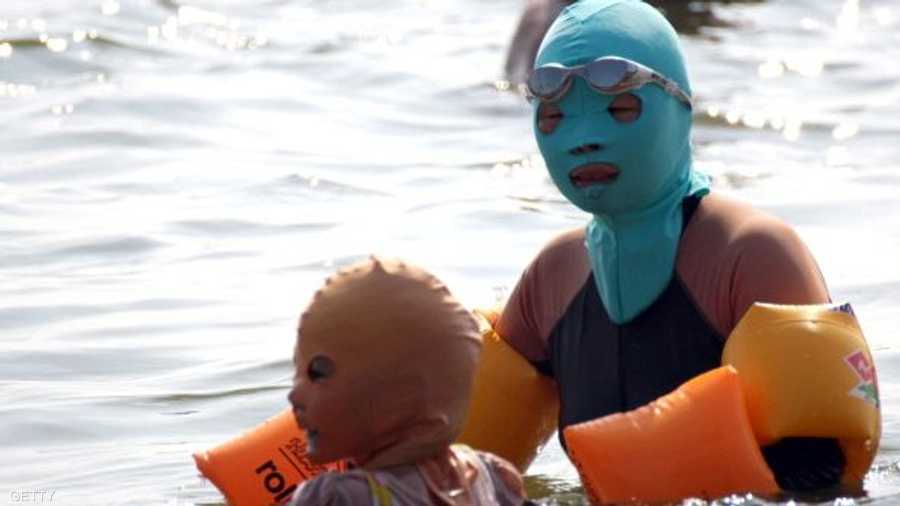 امرأة صينية وابنتها تضعان القناعين الواقيين من الشمس