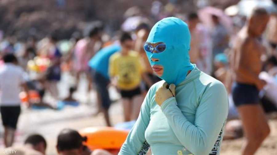 صينية ترتدي الزي الكامل الواقي من أشعة الشمس، بما في ذلك كفوف لليدين