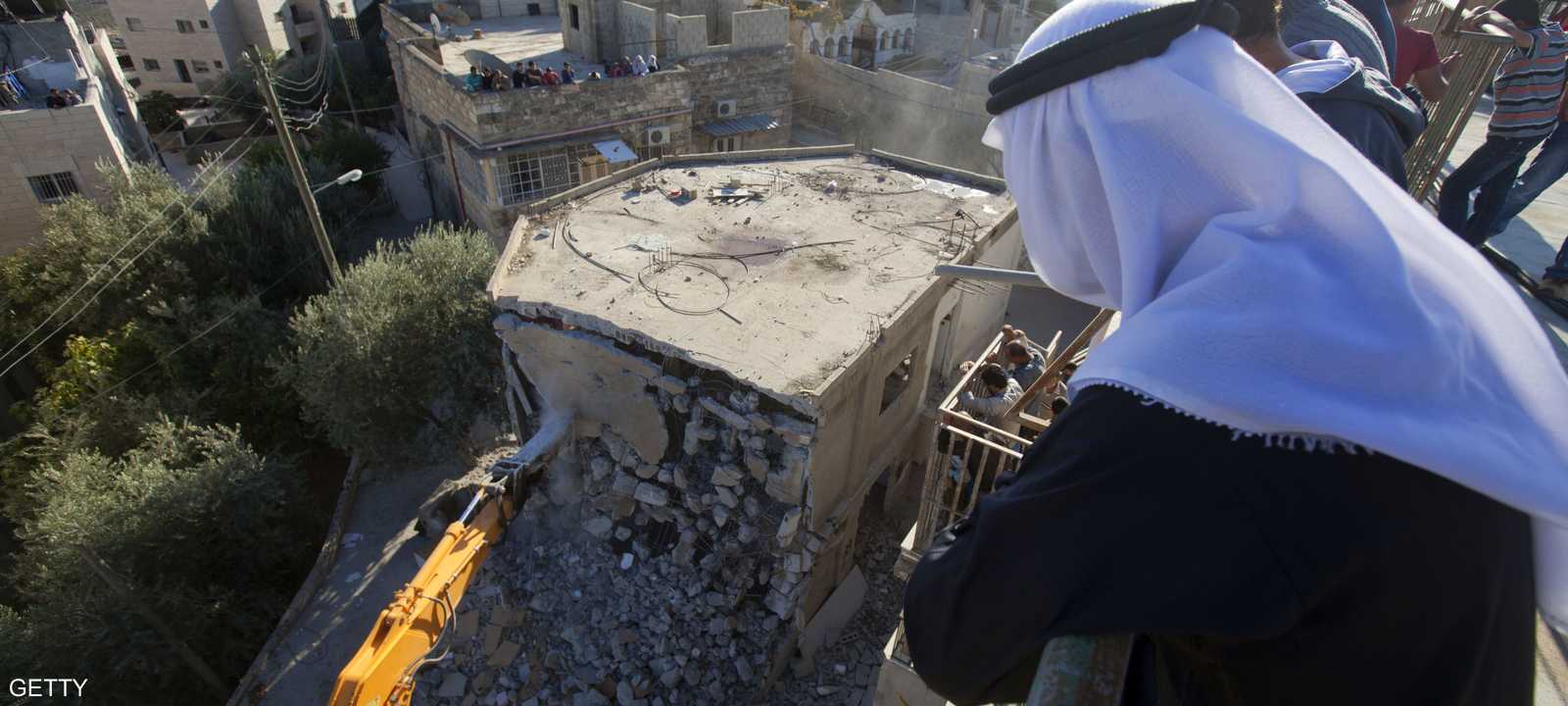 فلسطيني في القدس الشرقية يراقب بلدوزر إسرائيلي أثناء هدمه لبعض المنازل لتوسيع الاستيطان