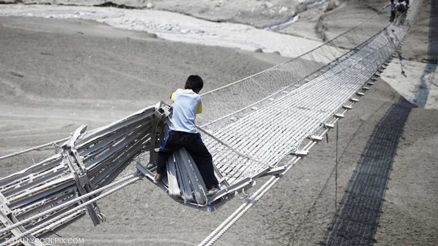 طفل يتحدى الخطر ويحاول عبور جسر دمرته الفيضانات في نيبال