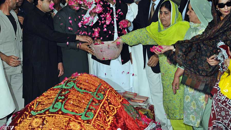 مواطنون باكستانيون يرشون الورود على ضريح بنظير بوتو.