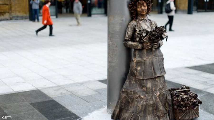 مؤدية أو تمثال بشري برونزي لامرأة بريطانية تنتظر في محطة القطارات