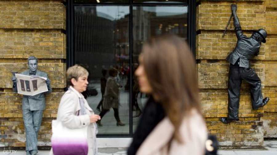 تشارلي شابلن متسلقا الجدار على جانب مدخل بناية، وعلى الجانب الآخر التمثال القارئ