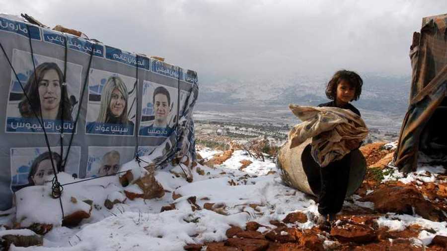 فتاة تحمل أغطية إضافية بجوار خيمة في مخيم للاجئين قرب قرية بوادي البقاع