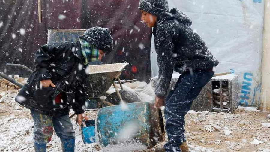 أطفال ينقلون أسطوانة غاز منزلي وسط الثلج إلى خيمتهم