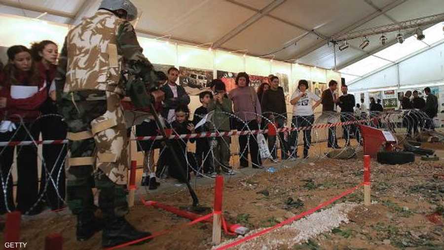 في لبنان.. شباب لبنانيون يشاهدون جندي بالجيش أثناء عملية كشف عن الألغام