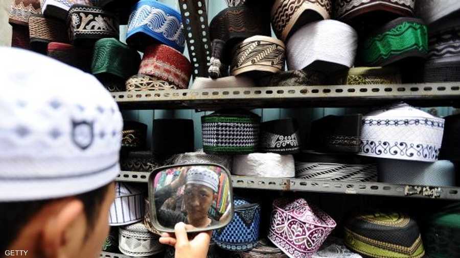 شاب يحتار في اختيار قبعة تقليدية من أحد المحال