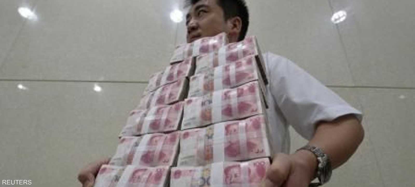 موظف يحمل عملات ورقية فئة 100 يوان ببنك في الصين