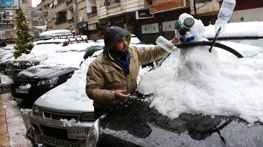 سوري يزيح الثلوج عن سيارته