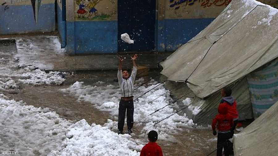 طفل فلسطيني يلعب بالثلج بمخيم اليرموك بسوريا