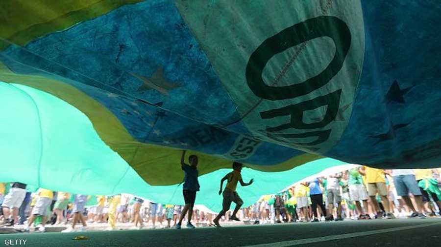 أطفال يركضون تحت علم ضخم للبرازيل