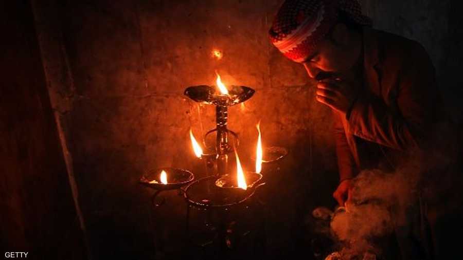 ورجل إيزيدي يضيء الشموع ومصابيح الكاز خارج معبد لالش النوراني