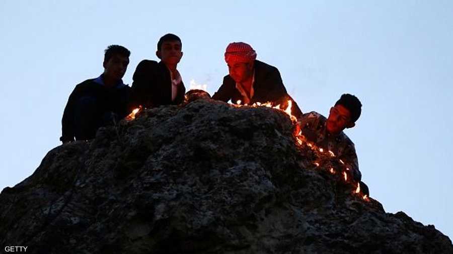رجال إيزيديون يضيئون مصابيح الكاز خارج معبد لالش