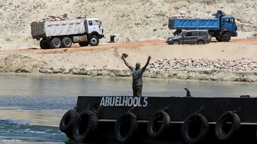 مصري يلوح لقارب يعبر في قناة السويس الجديدة