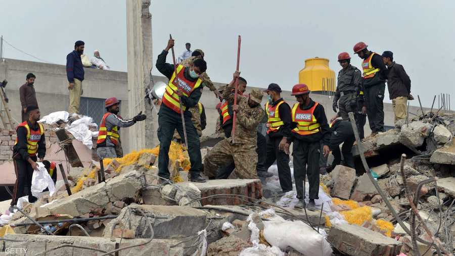 رجال من فرق الإنقاذ في مكان انهيار مبنى المصنع.