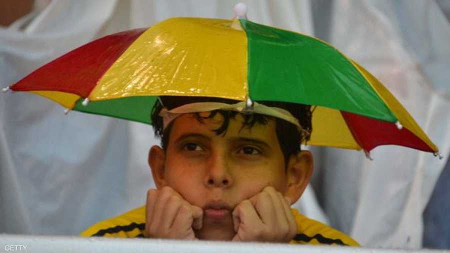 يحتمي من المطر بمظلة بألوان علم بلاده