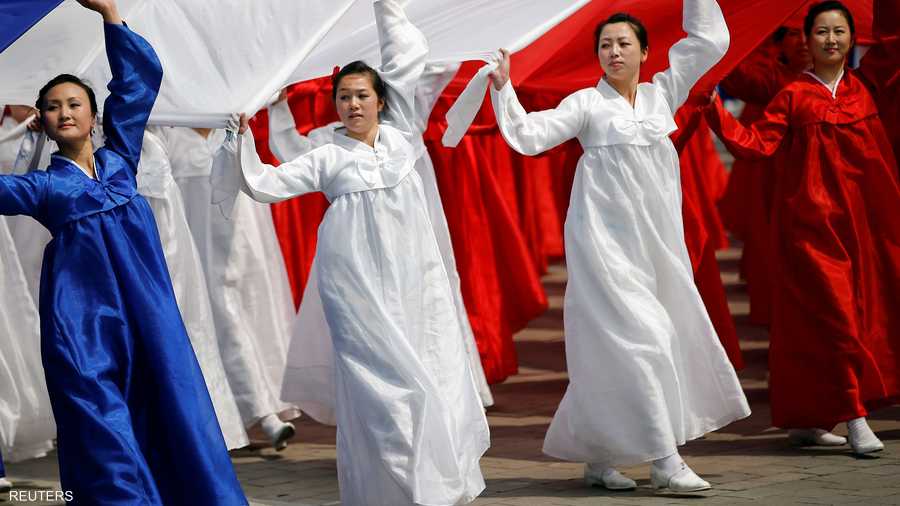 يرتدين ألوان علم كوريا الشمالية ويلوحن به