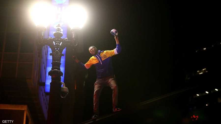 أحد مشجعي الفريق محتفلا بالتعلق على عامود إنارة خارج الملعب.