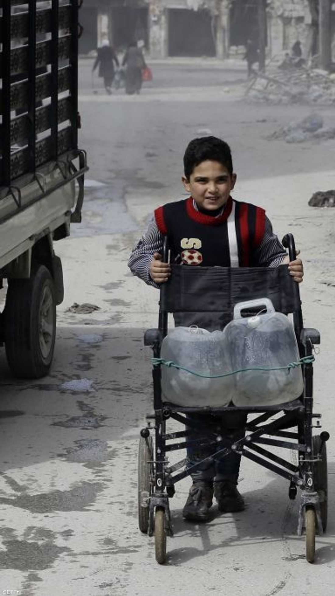 طفل سوري ينقل الماء بواسطة الكرسي المتحرك