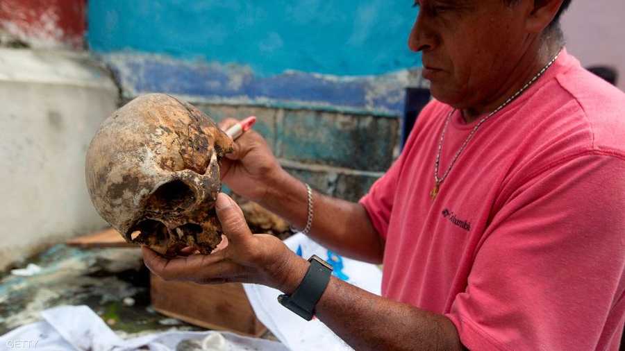 أحد سكان قبائل المايا يقوم بالرسم على أحدى الجماجم