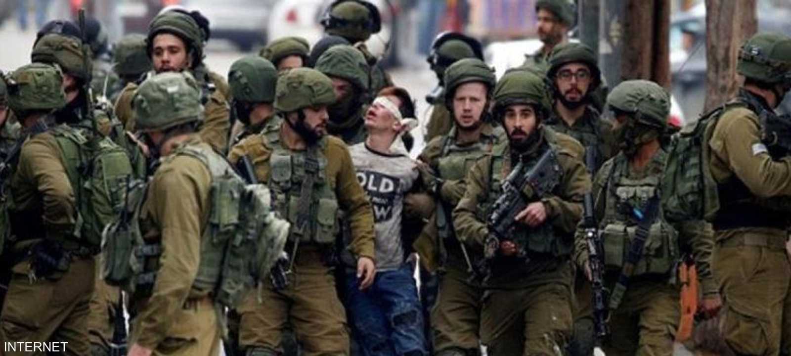 الجنود الإسرائيليون يقتادون الفتى وهو معصوب العينين.
