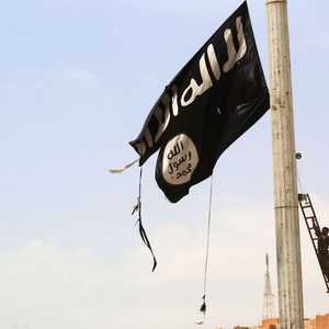 أحد عناصر سوريا الديمقراطية يقوم بإنزال علم داعش - أرشيف