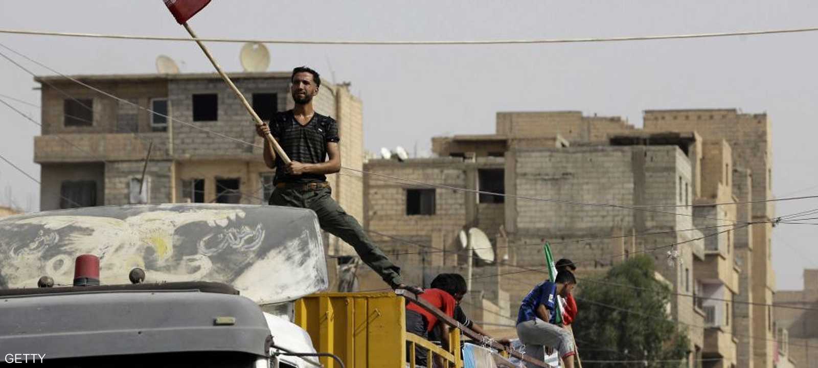 سوري يرفع علما إيرانيا فوق شاحنة مساعدت قادمة من طهران