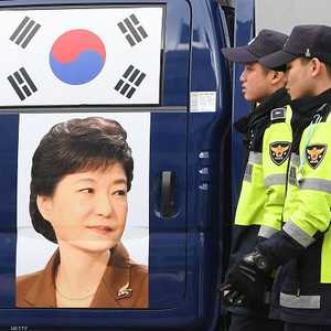 رجال أمن يمرون أمام ملصق لرئيس كوريا الجنوبية السابقة.