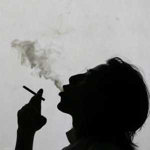 رجل ينفث دخان سيجارته في الهواء.