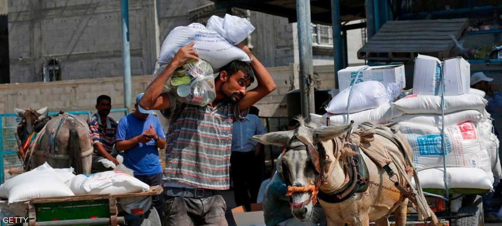 رجل فلسطيني يحمل كيسا من الدقيق خارج مركز توزيع المساعدات