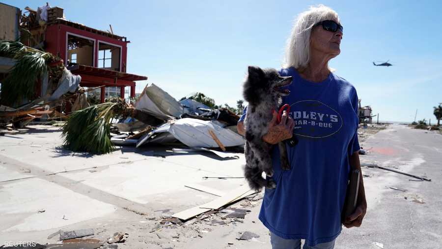 تحمل كلبها وهي تتأمل ما أحدثه الإعصار