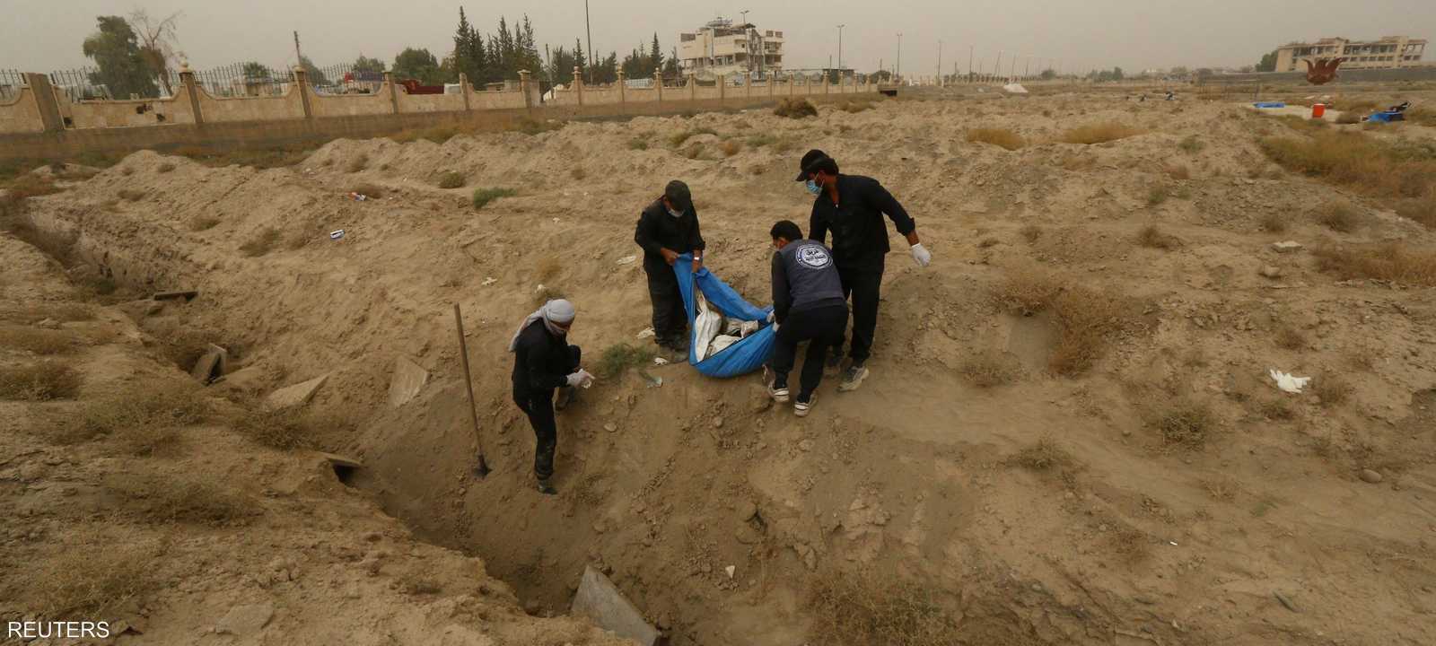 ينتشلون جثة من إحدى المقابر الجماعية المحيطة بمدينة الرقة.