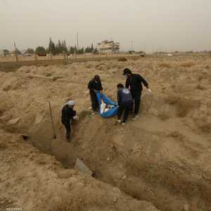ينتشلون جثة من إحدى المقابر الجماعية المحيطة بمدينة الرقة.