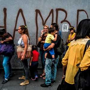 طابور من الفقراء في كاراكاس وعلى الحدار كتبت كلمة الجوع