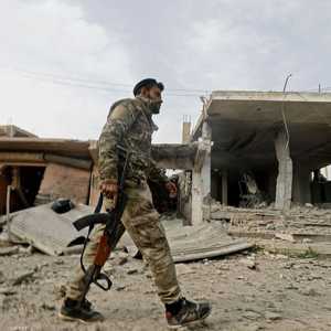 مقاتل قوات سوريا الديمقراطية أمام مقر سابق داعش بمدينة هجين