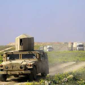 سيارة هامر تحرس شاحنات تقل أفرادا يعتقد أنهم من داعش