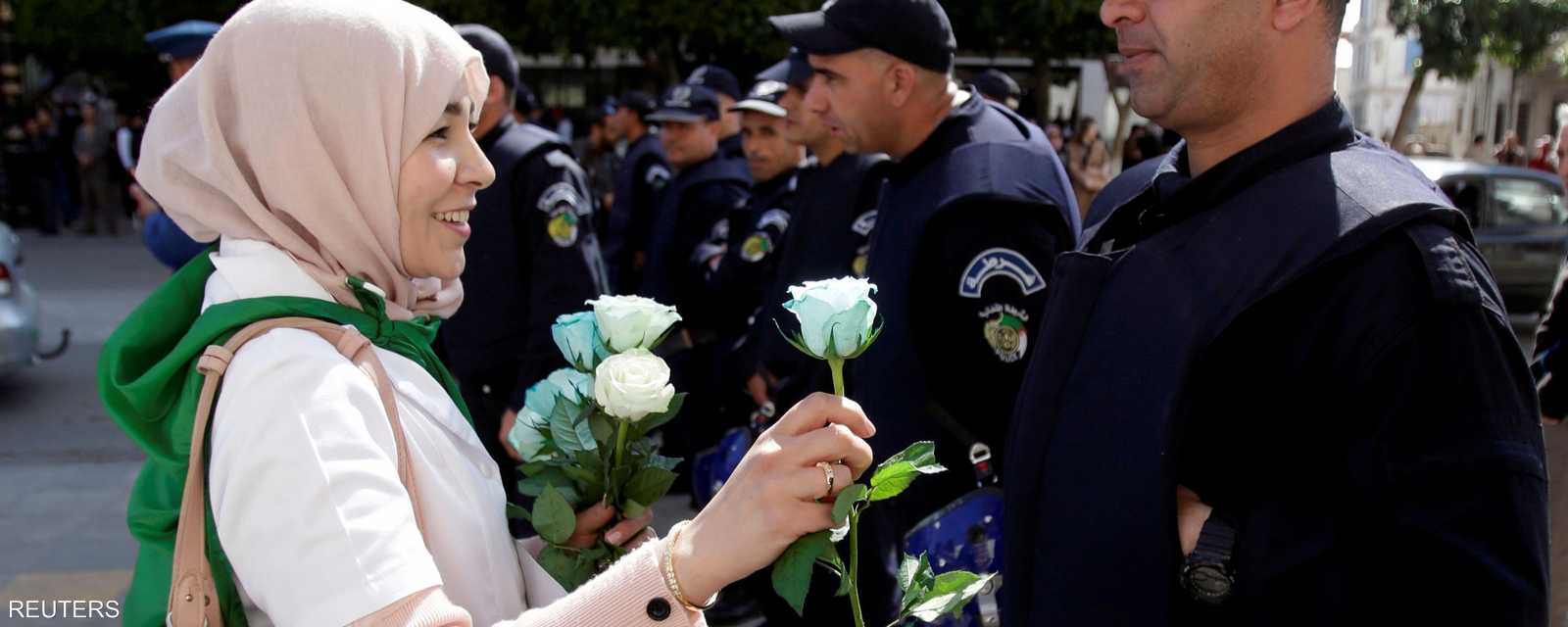 إحدى المتظاهرات تقدم زهورا إلى ضابط شرطة