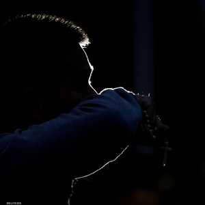 رجل يحمل مسبحة يمسح وجهه وهو يدعو لضحايا هجمات المسجد