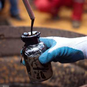 أحد العمال يقوم بجمع عينة من النفط الخام