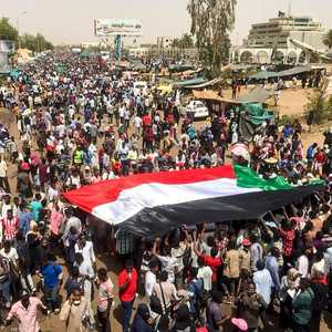 متظاهرون يرفعون علم السودان