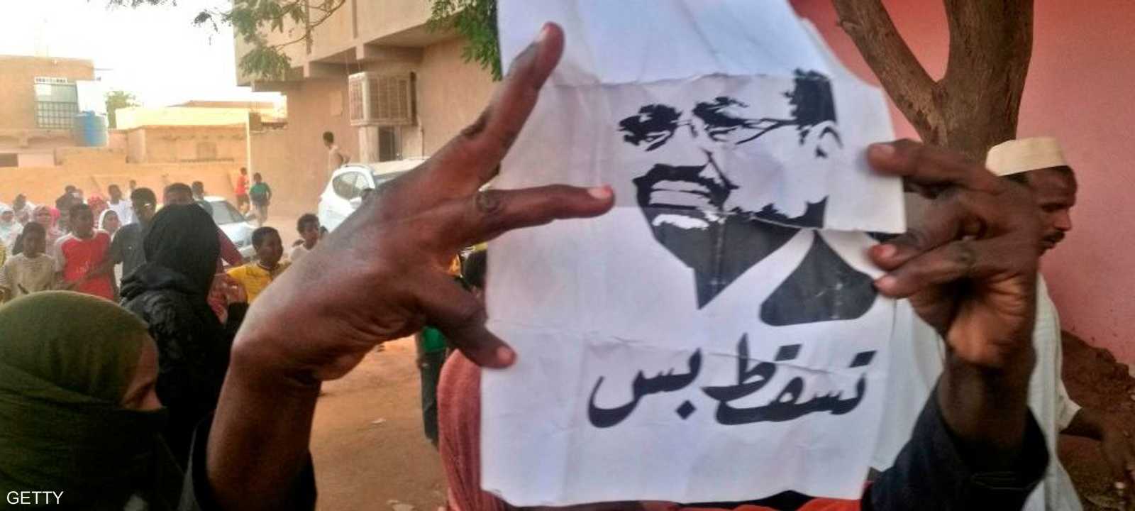 سودانية تحمل شعار الحراك السوداني في بداياته