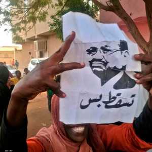 سودانية تحمل شعار الحراك السوداني في بداياته