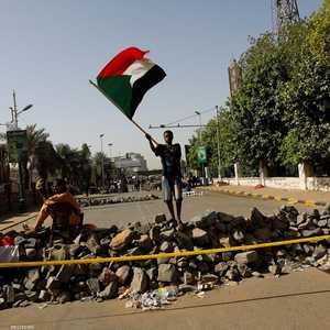 متظاهر سوداني يرفع علم بلاده أمام عوائق أمام موقع الاعتصام.