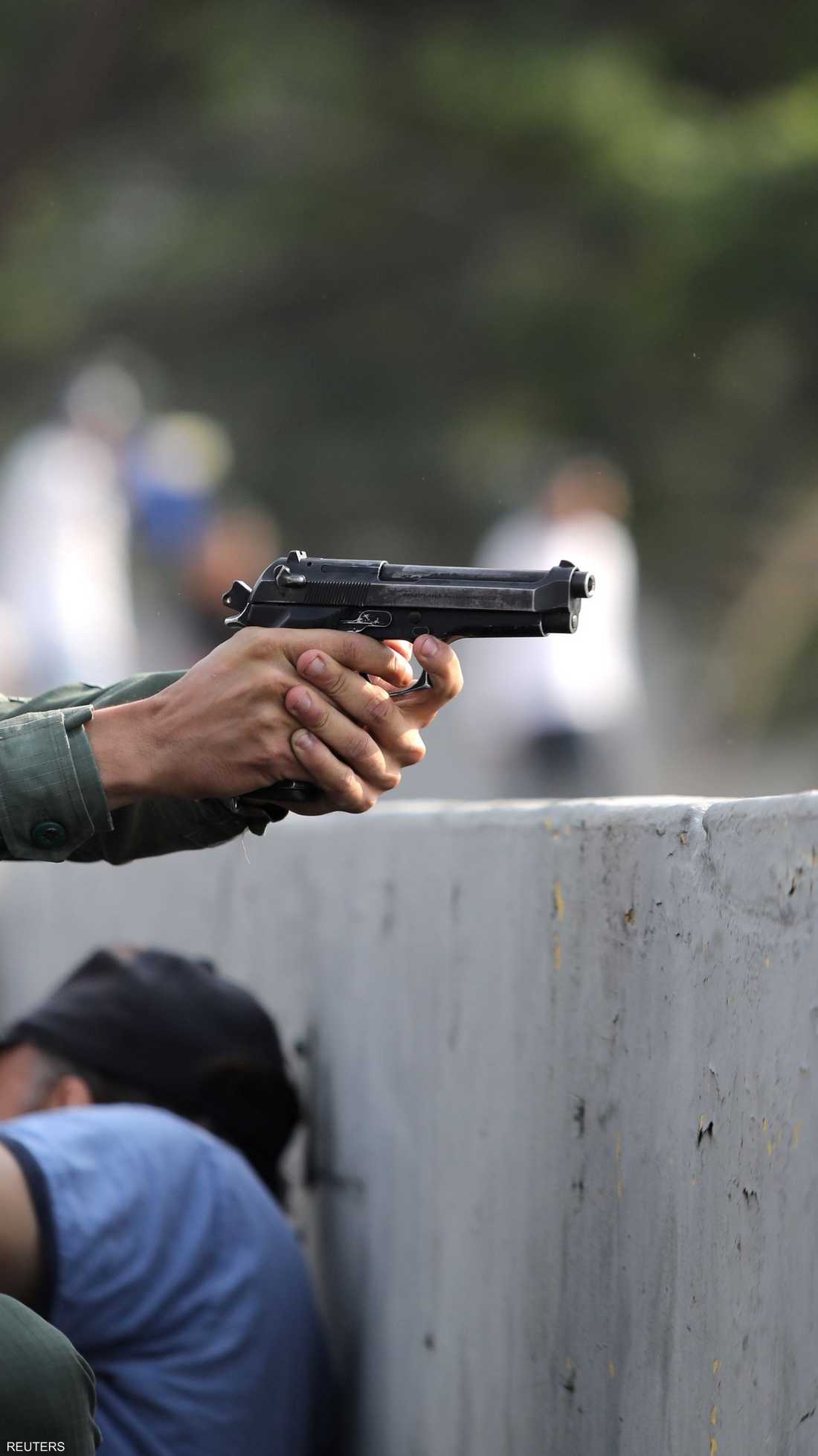 عسكري فنزويلي يشهر سلاحه خلال اشتباكات مع قوات الأمن قرب قاعدة جوية في كاراكاس